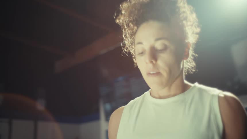 A woman exercises by lifting small weights while in a gymnasium