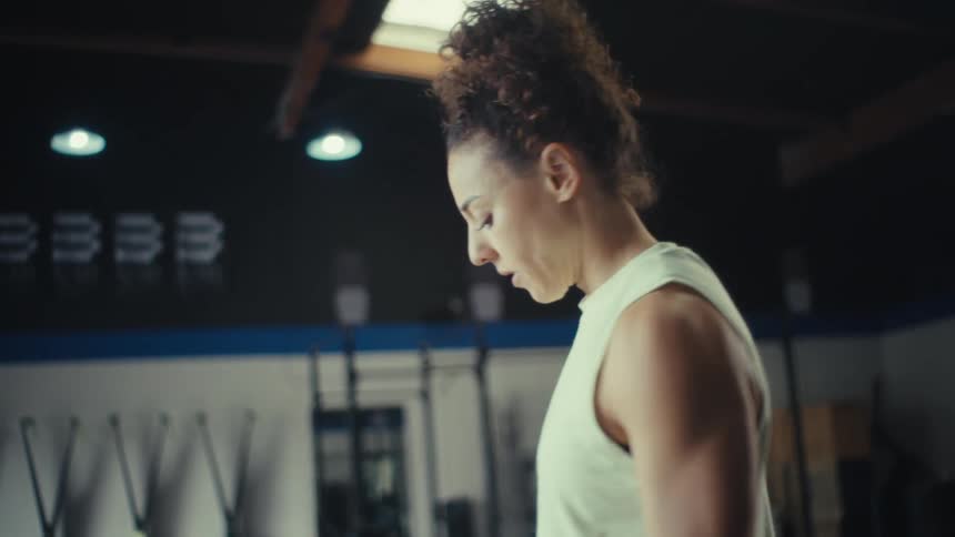 The woman is curling barbells in the gym