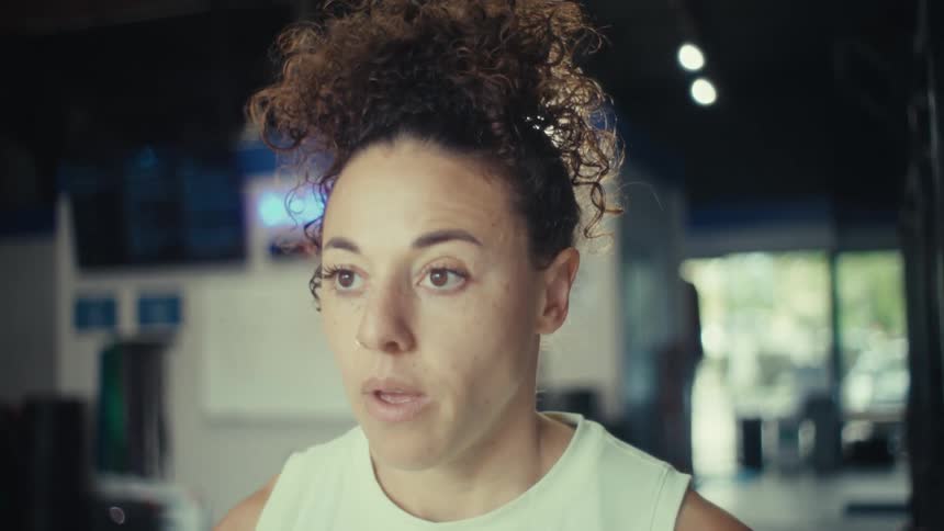 The woman is lifting barbells in the gym