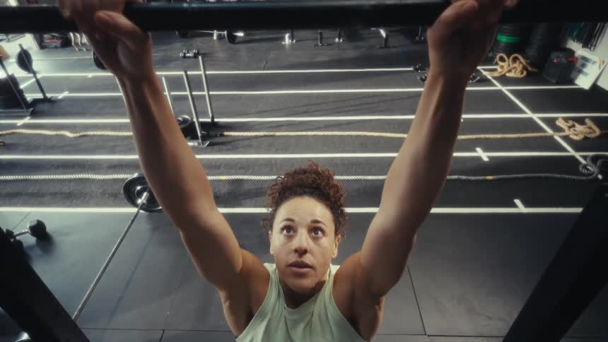 Young woman looks up at a workout bar and exercises doing chin ups