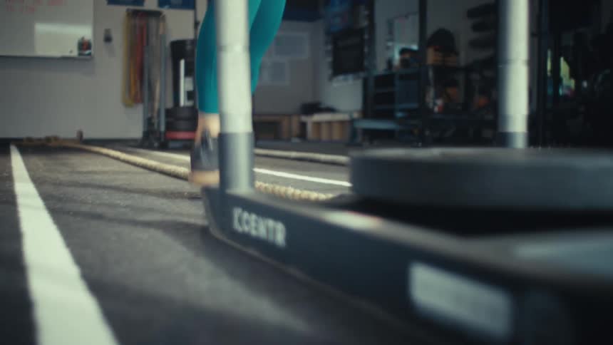 Young woman runs as she exercises pushing weights across the gym