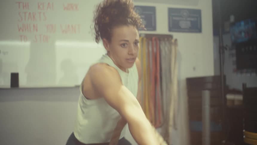 Woman pulls a rope during an intense workout in a gym
