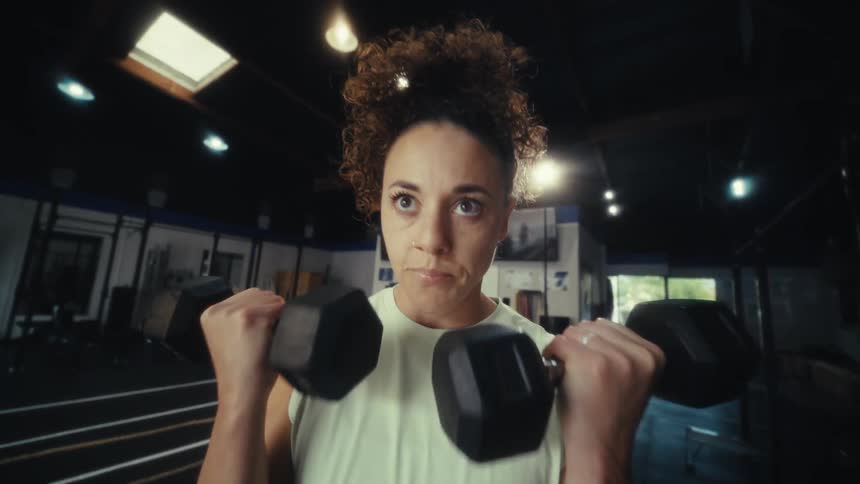 Woman performs a dumbbell exercise in a gym