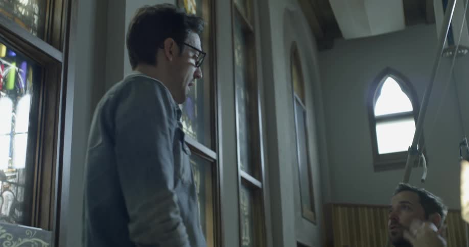 Two men talk while standing inside a building