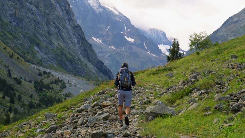 A man in shorts hikes a rocky path