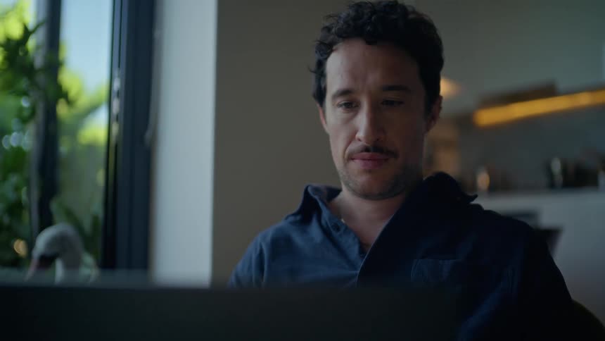 Man sitting in front of a laptop computer as he looks around