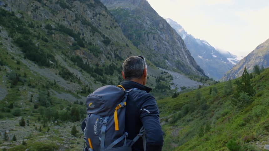 Man wearing a backpack looks out at mountains