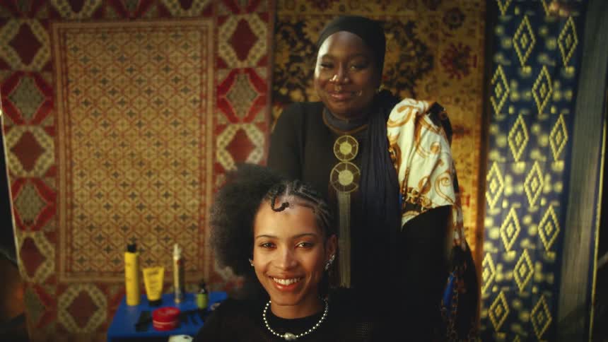 Two women smile in a salon while one styles the others hair