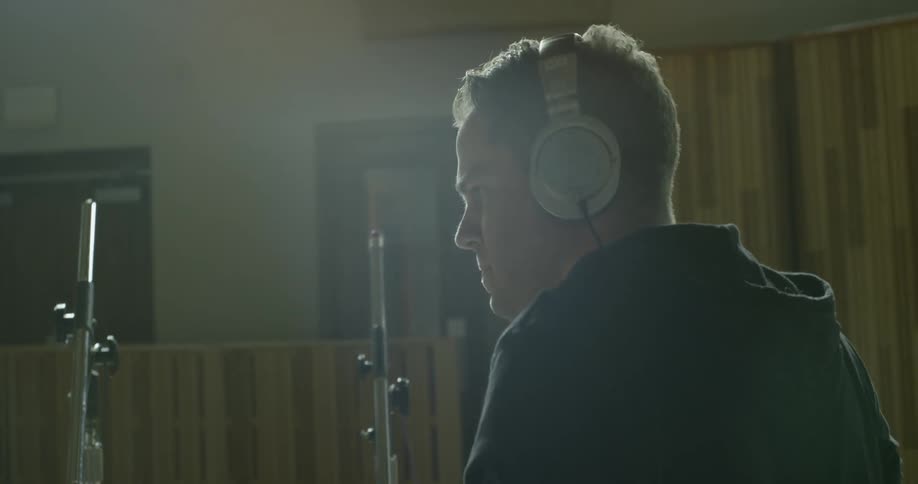 A man plays the drums while wearing headphones