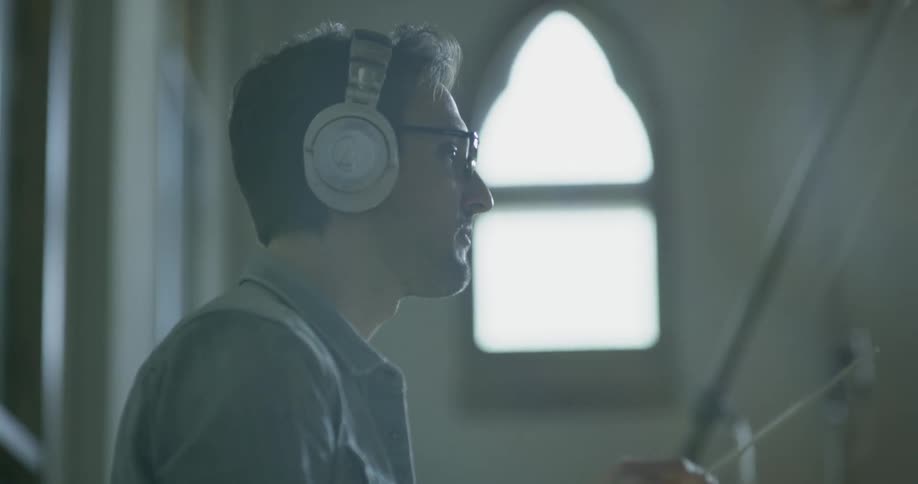 A man in headphones conducts an orchestra