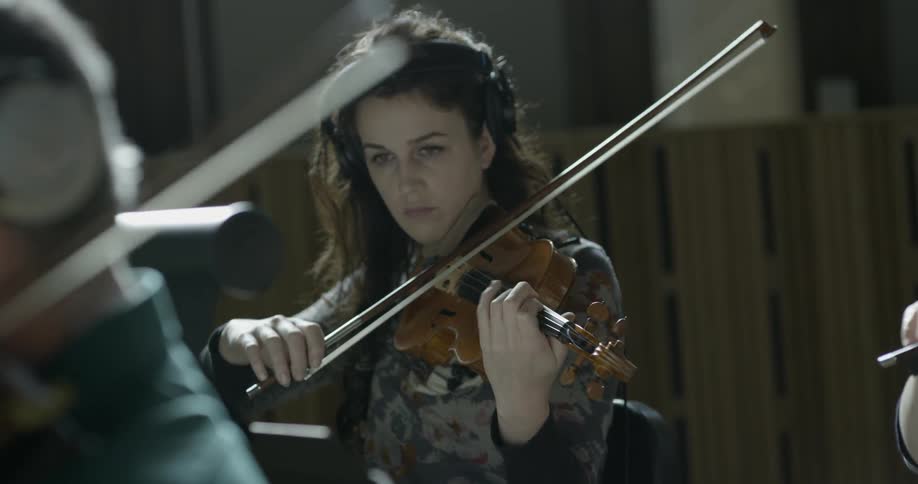 Woman playing the violin with other people playing instruments