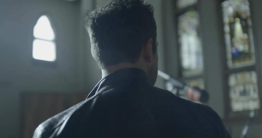 A man in a leather jacket looks around a church
