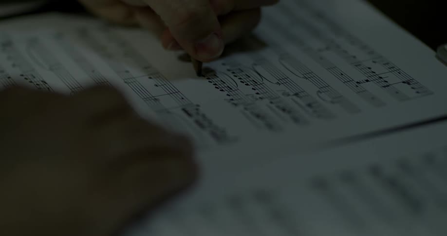 A person makes notes on a sheet of music