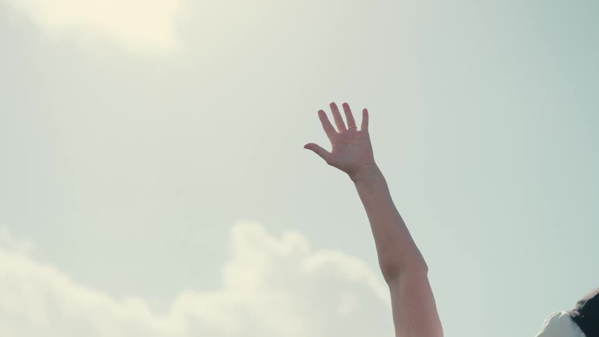 Outstretched arm with open hand against a clear sky with clouds