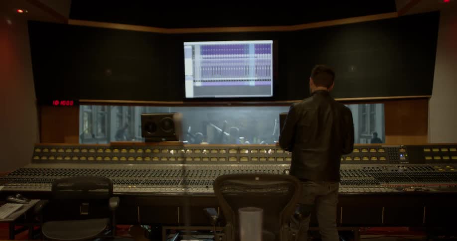 Man standing at a control board in a music studio