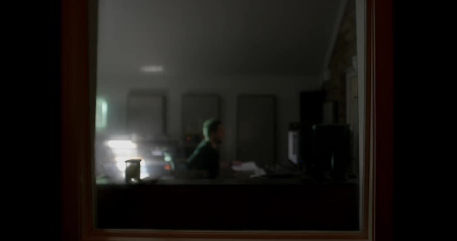 A man picks up some papers and sits down at a desk