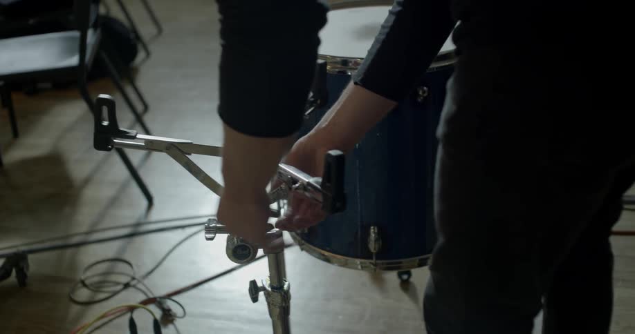 A person adjusts a drum set