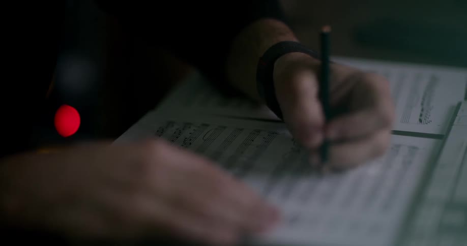 Person writing on sheet music