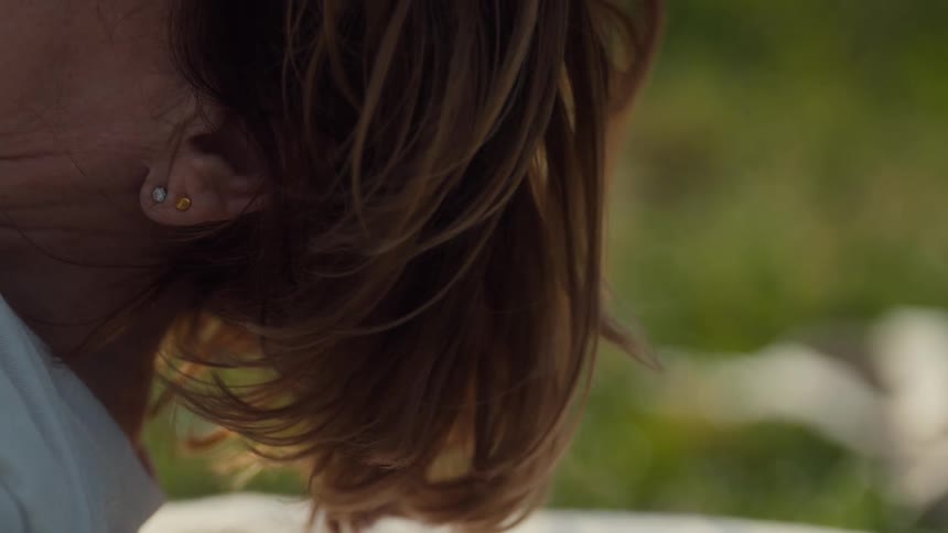 Hair of an adult woman lying down on the floor moving her head outdoors during day time