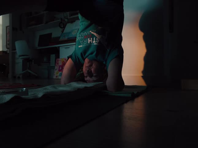 The woman is doing a handstand at home
