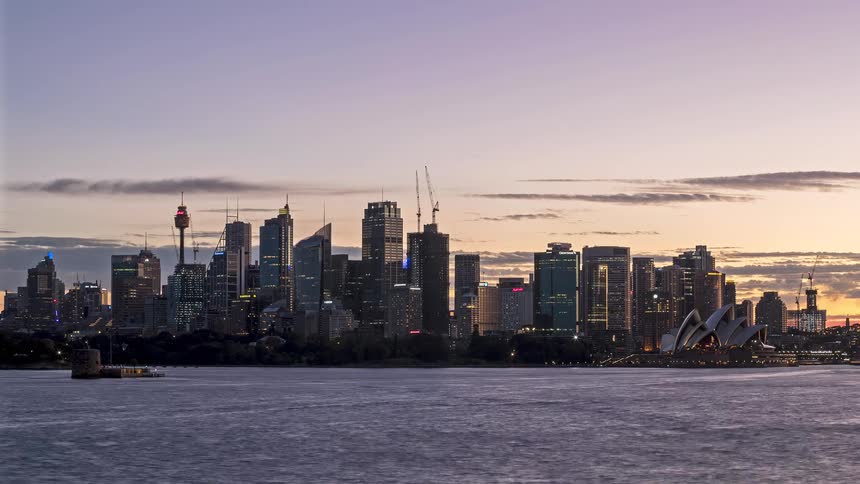 Watercraft move through the water passing sydney as night falls