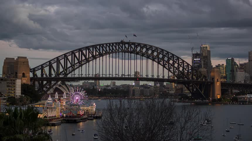 Boats and cars travel over and under the bridge in the city