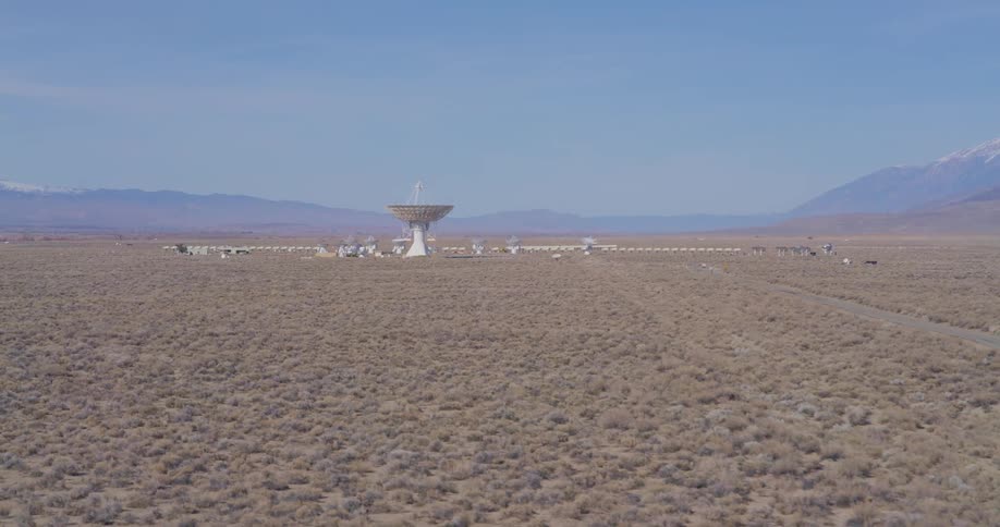 Large central satellite dish surrounded by smaller ones on an arid plain