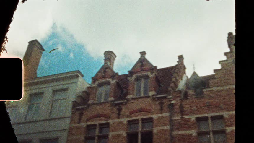 Historic facades with stepped roofs and tall windows under a partly cloudy sky