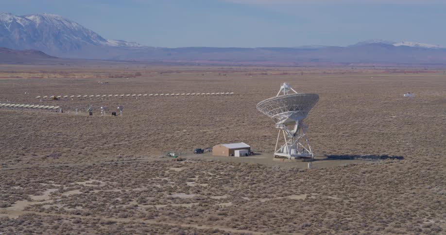 Isolated satellite dish beside a small building on a vast desert plain