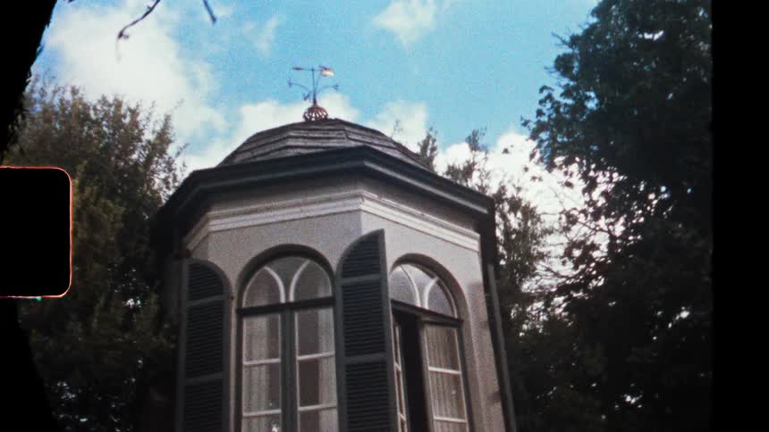 Pavilion with arched windows and open shutters under a blue sky with clouds