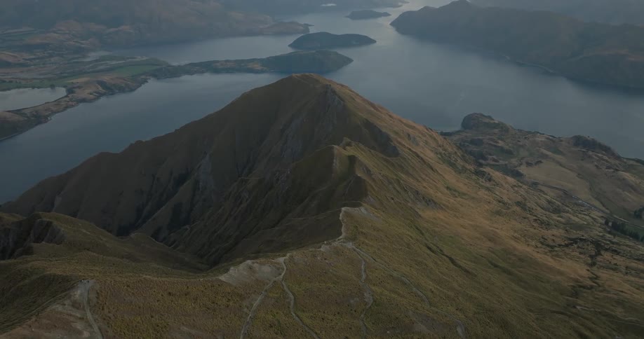 Peak of a mountain next to a lake with other mountains and islets around outdoors during day time