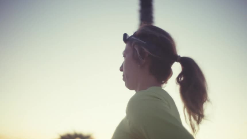 Woman runs at dusk wearing a headlamp in an outdoor setting