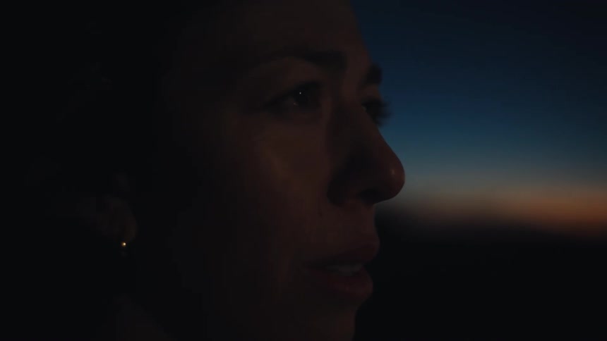 Adult woman looking at the horizon with a contemplative facial expression in a natural landscape outdoors during dusk or dawn