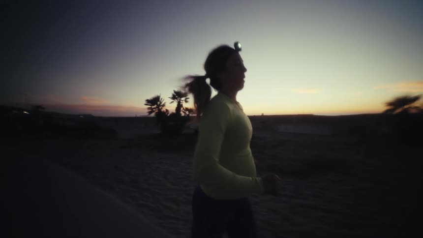 Woman wearing a headlamp as she jogs at dusk