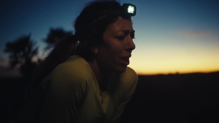 Runner wearing a headlamp breathes with effort at dusk