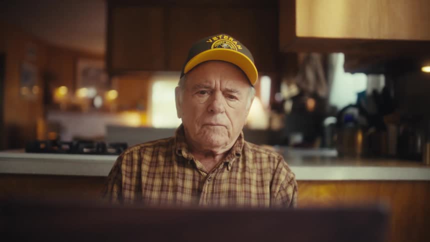 Man sitting at a table looking at a laptop computer and just thinking