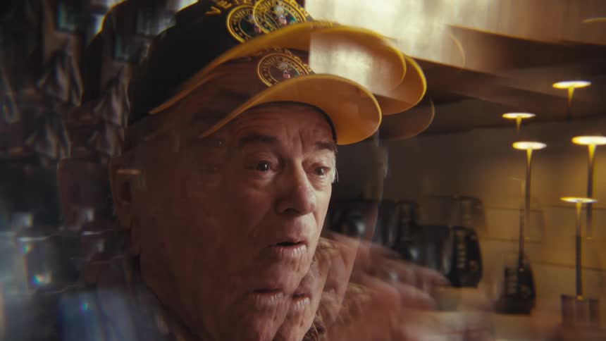 Elderly man smiling with veteran cap in home kitchen with mirrored effect