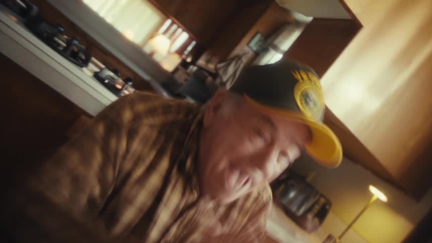 Elderly man wearing cap in motion inside home kitchen
