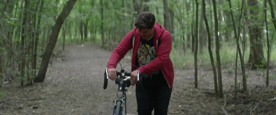 Man walks his bike through the woods