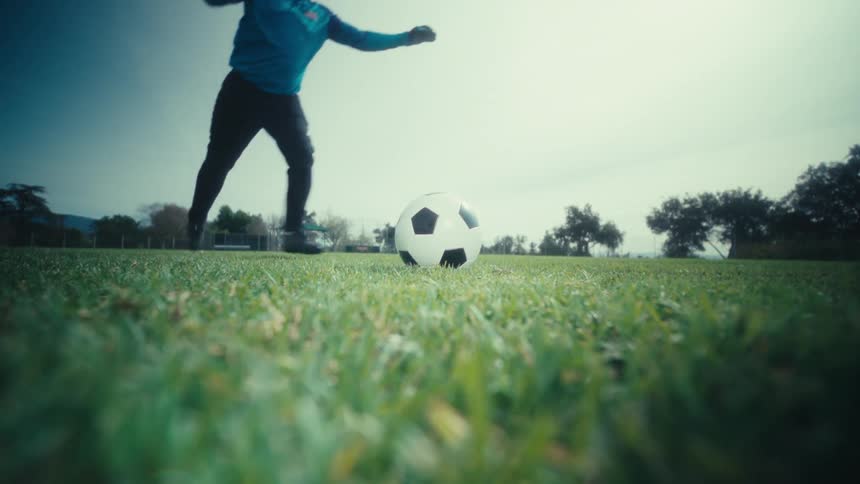 Person kicks a soccer ball on a grassy field outdoors