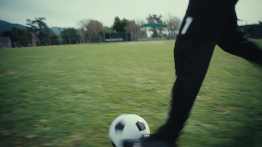 Soccer player kicks the soccer ball across the field