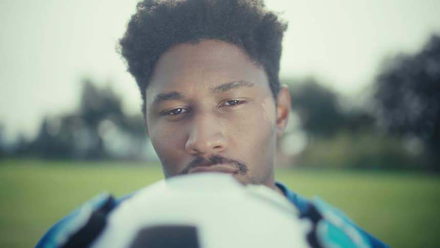 Soccer player stands in the field holding a soccer ball