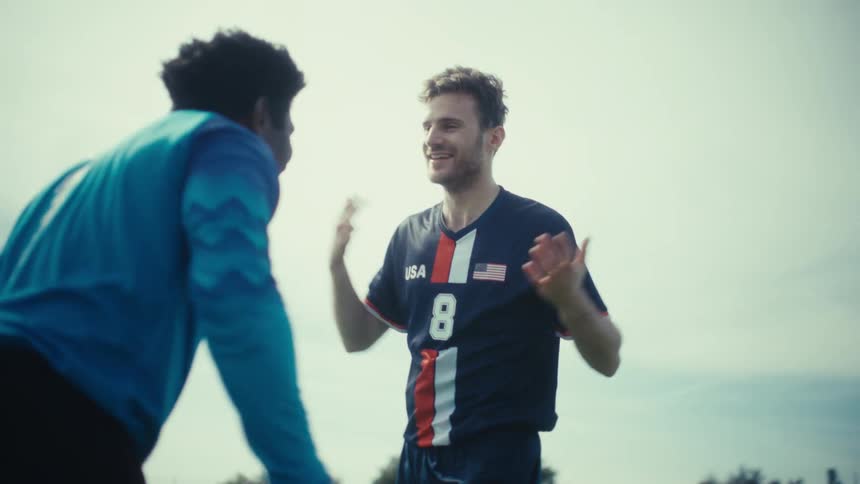 Soccer players celebrate with a high five on an outdoor field