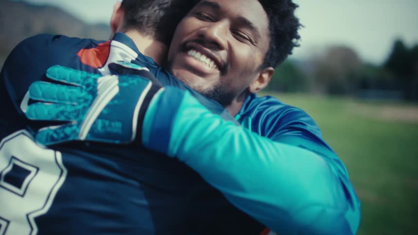 Goalkeeper greeting a soccer player with a hug