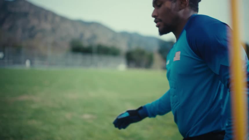 Soccer ball sits on the grass in a field as a player kicks it away
