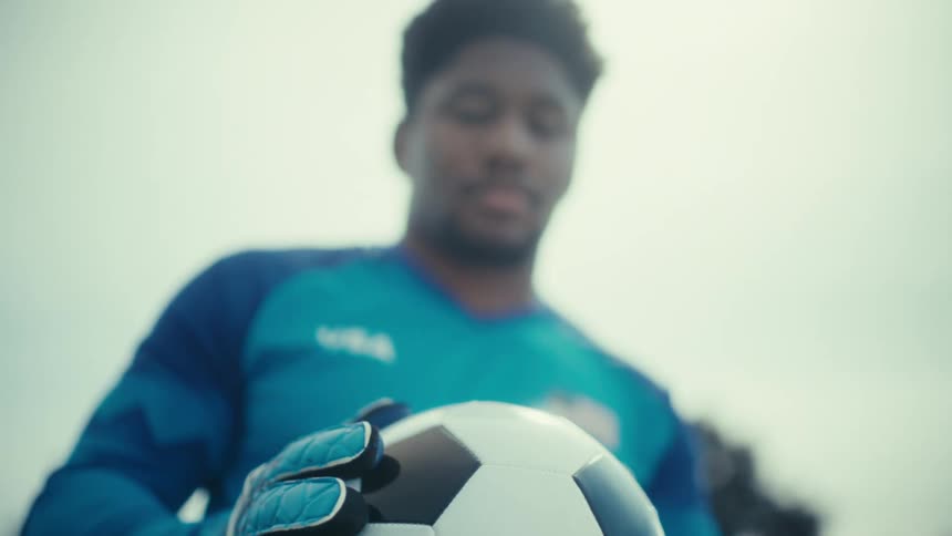The man lifts the soccer ball up and examines it