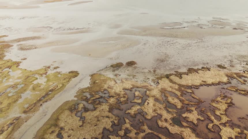 A wide stretch of land with a dry water body near the coast at midday
