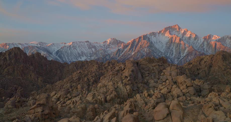 Sunlit snowy peaks above rugged rocky formations