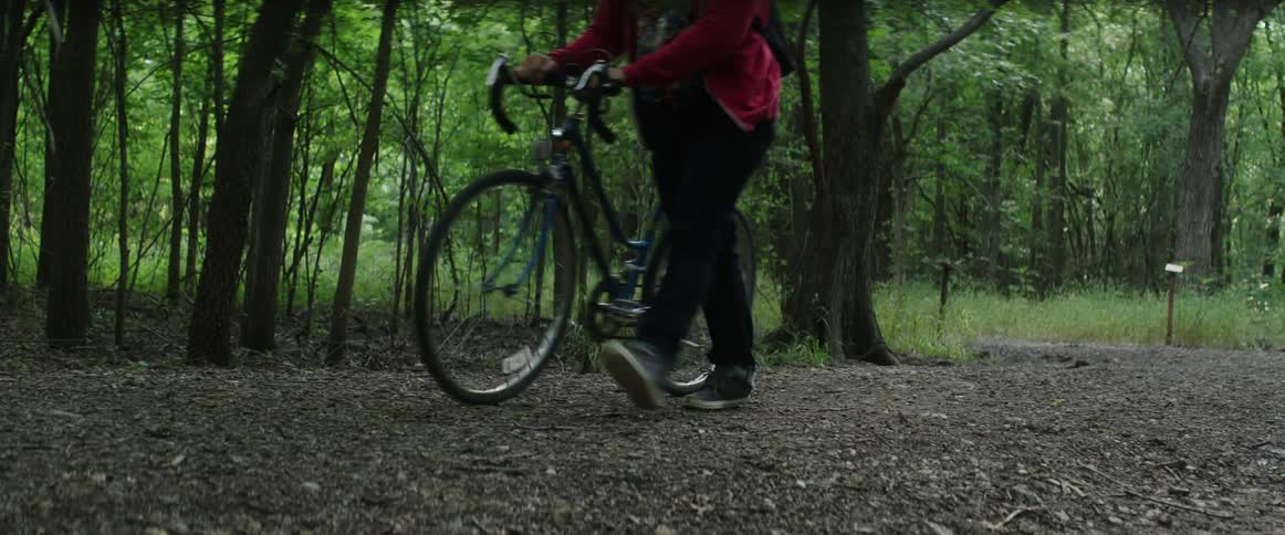 Man walks his bike through the woods