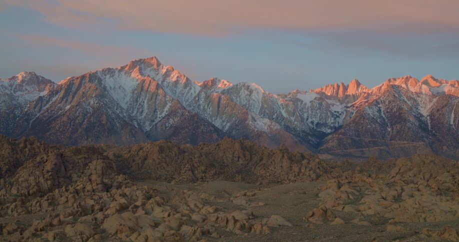 Sunlit snowy peaks above arid rocky terrain